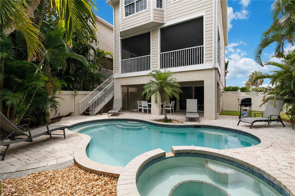 A multi-story house with a screened balcony overlooks a backyard pool and attached hot tub — 215 81ST STREET, HOLMES BEACH, FL