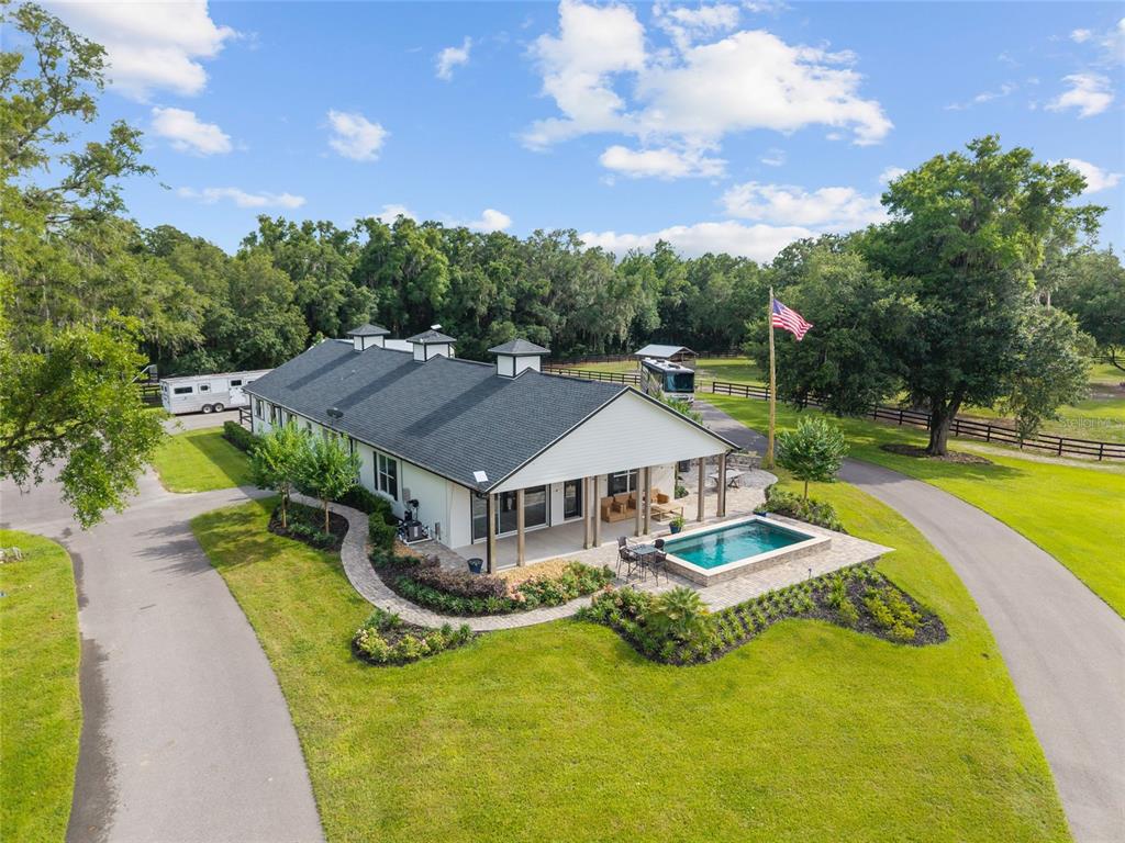 An aerial view shows a white house with a black roof, pool, and surrounding grounds — 11140 NW 160TH AVENUE, MORRISTON, FL