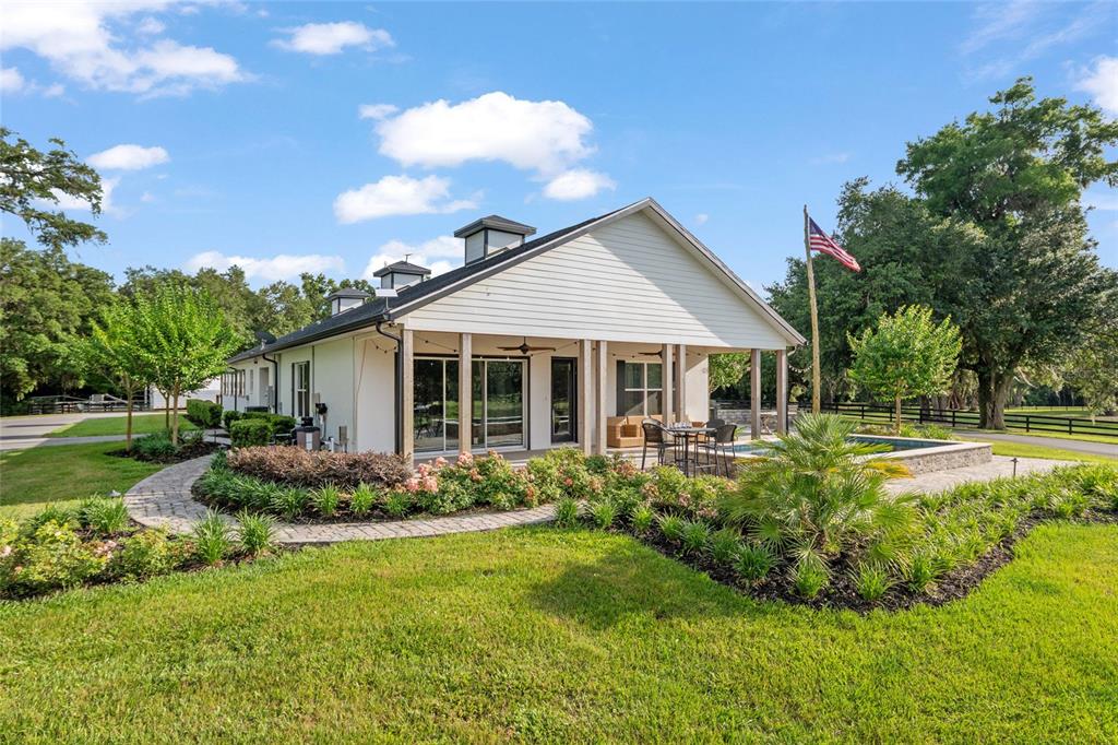 A white house with a covered patio, pool, and American flag on a grassy lot — 11140 NW 160TH AVENUE, MORRISTON, FL