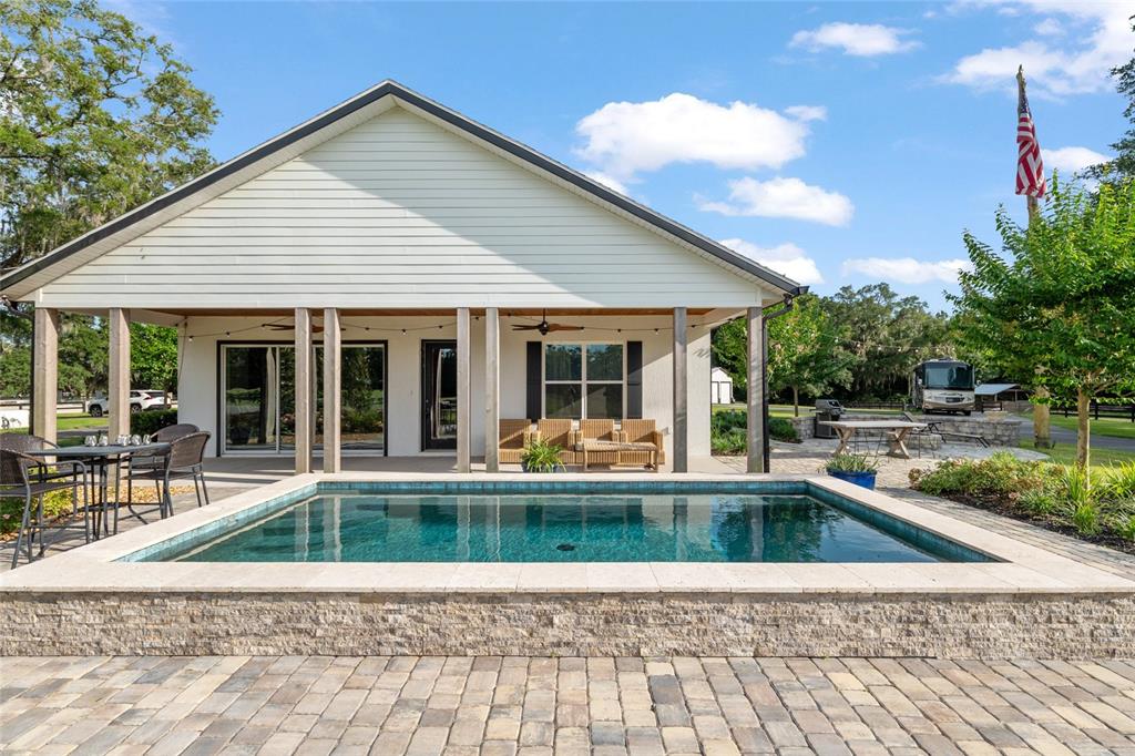 A rectangular swimming pool sits on a stone patio in front of a house — 11140 NW 160TH AVENUE, MORRISTON, FL