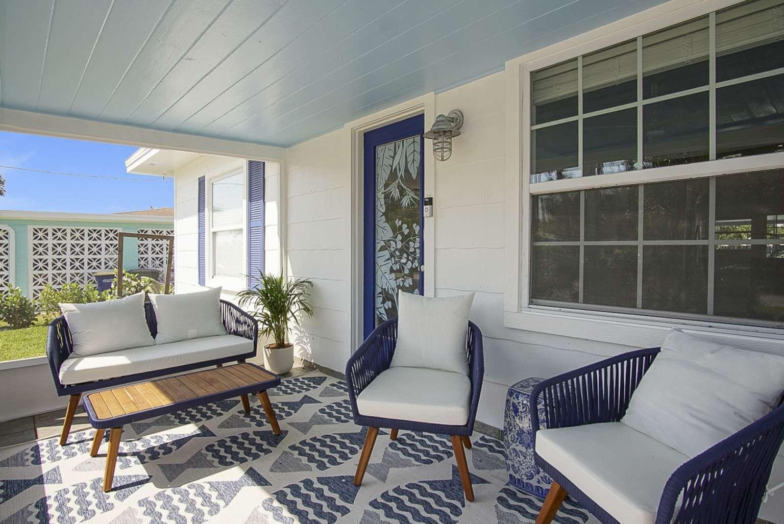 A covered porch features blue furniture, a patterned rug, and a glass-paneled front door — 307 Granada Street, Fort Pierce FL 34949, FORT PIERCE, FL