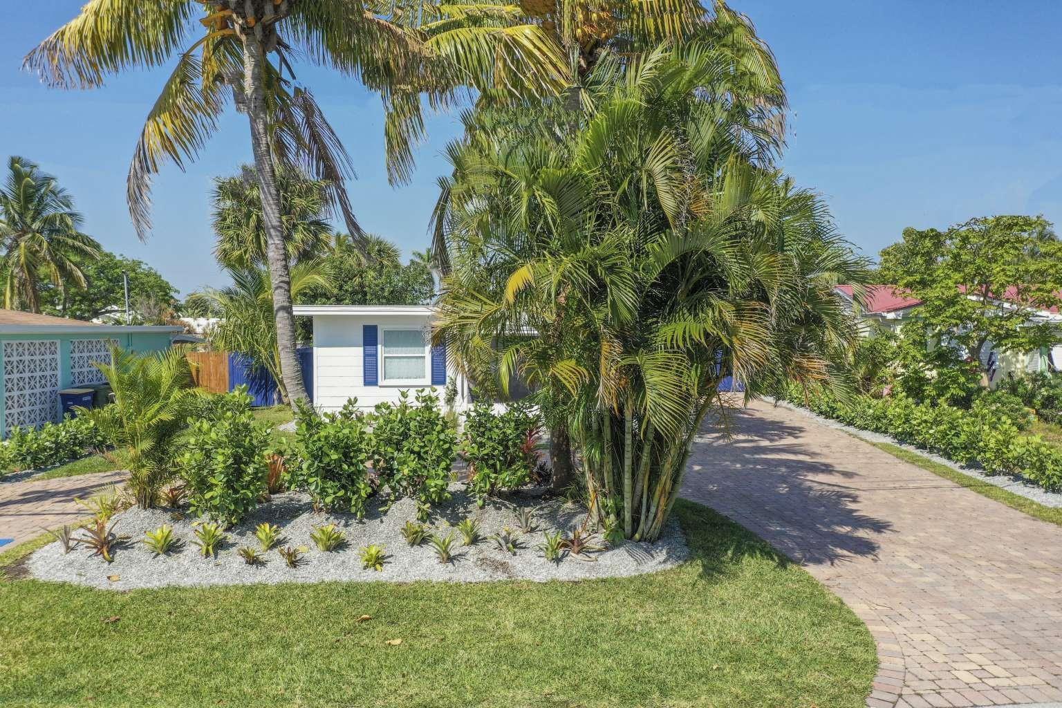 A white house with blue shutters sits behind a palm tree and a paved driveway — 307 Granada Street, Fort Pierce FL 34949, FORT PIERCE, FL