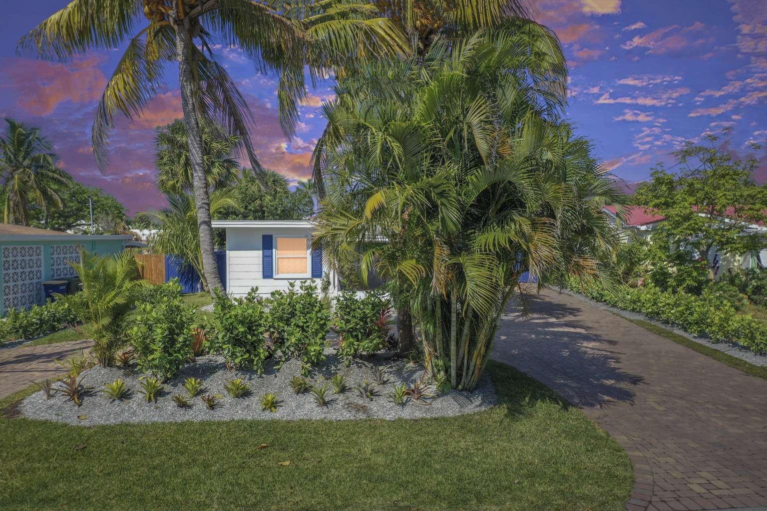 A white house with blue shutters sits behind a landscaped yard and palm trees — 307 Granada Street, Fort Pierce FL 34949, FORT PIERCE, FL