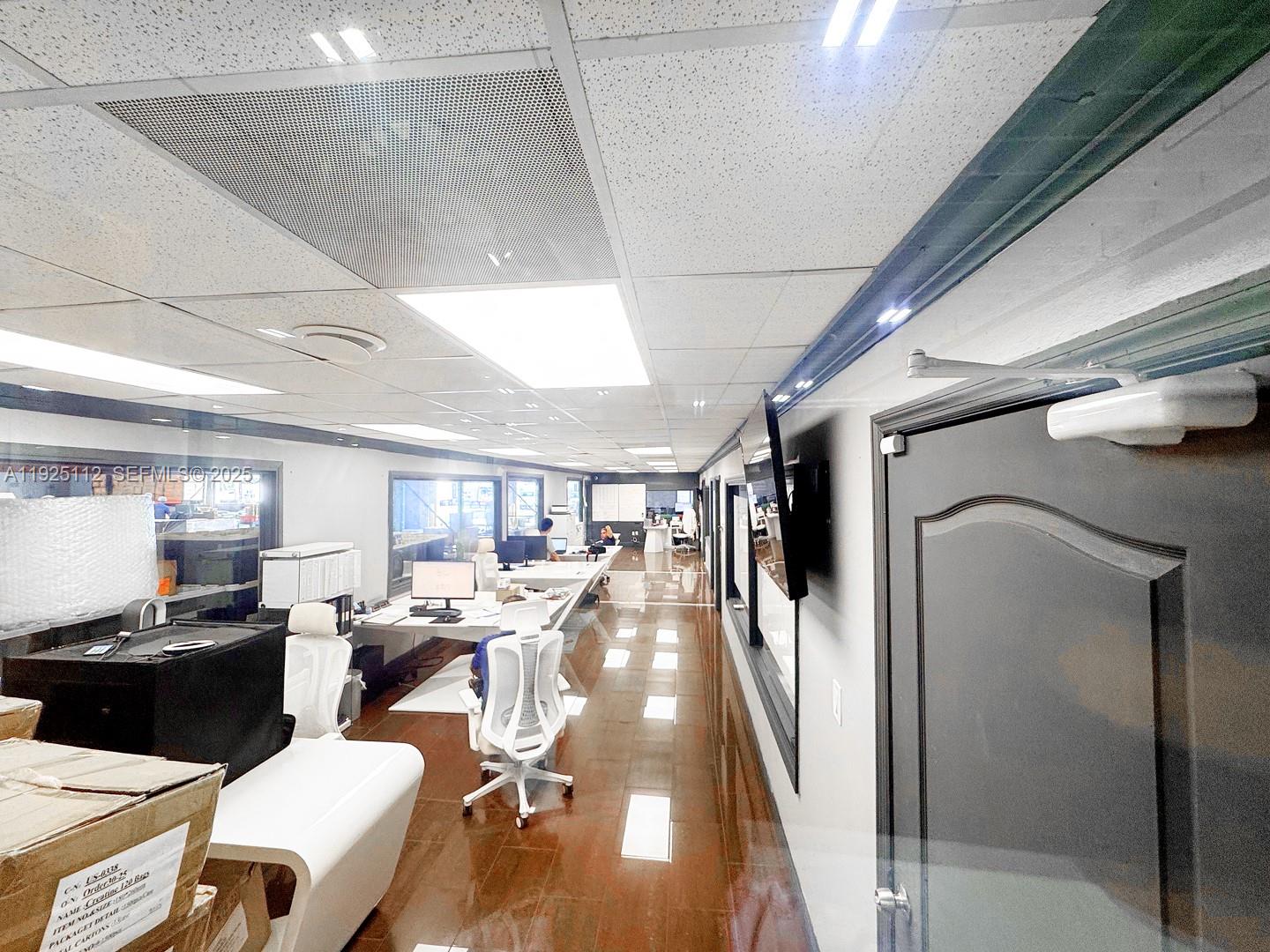 An office space features a long row of desks, white chairs, and glossy wood flooring — 1950 NW 70th Ave # 1970, Miami FL 33126, MIAMI, FL