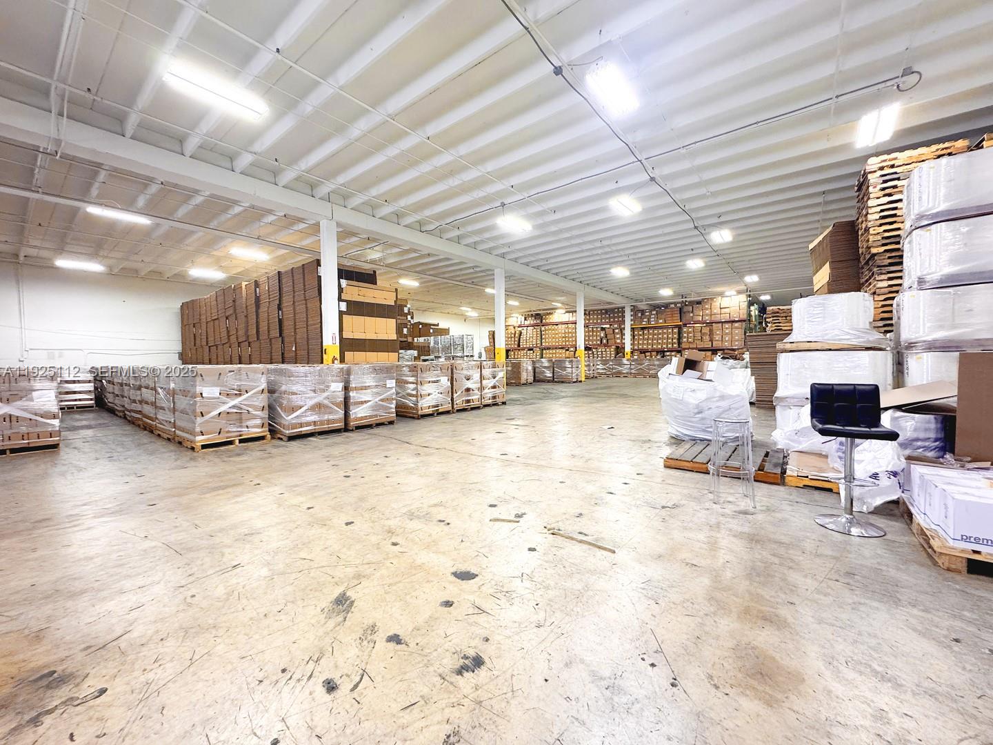 A large, open warehouse space features concrete floors, exposed ceiling beams, and stacked palletized inventory — 1950 NW 70th Ave # 1970, Miami FL 33126, MIAMI, FL