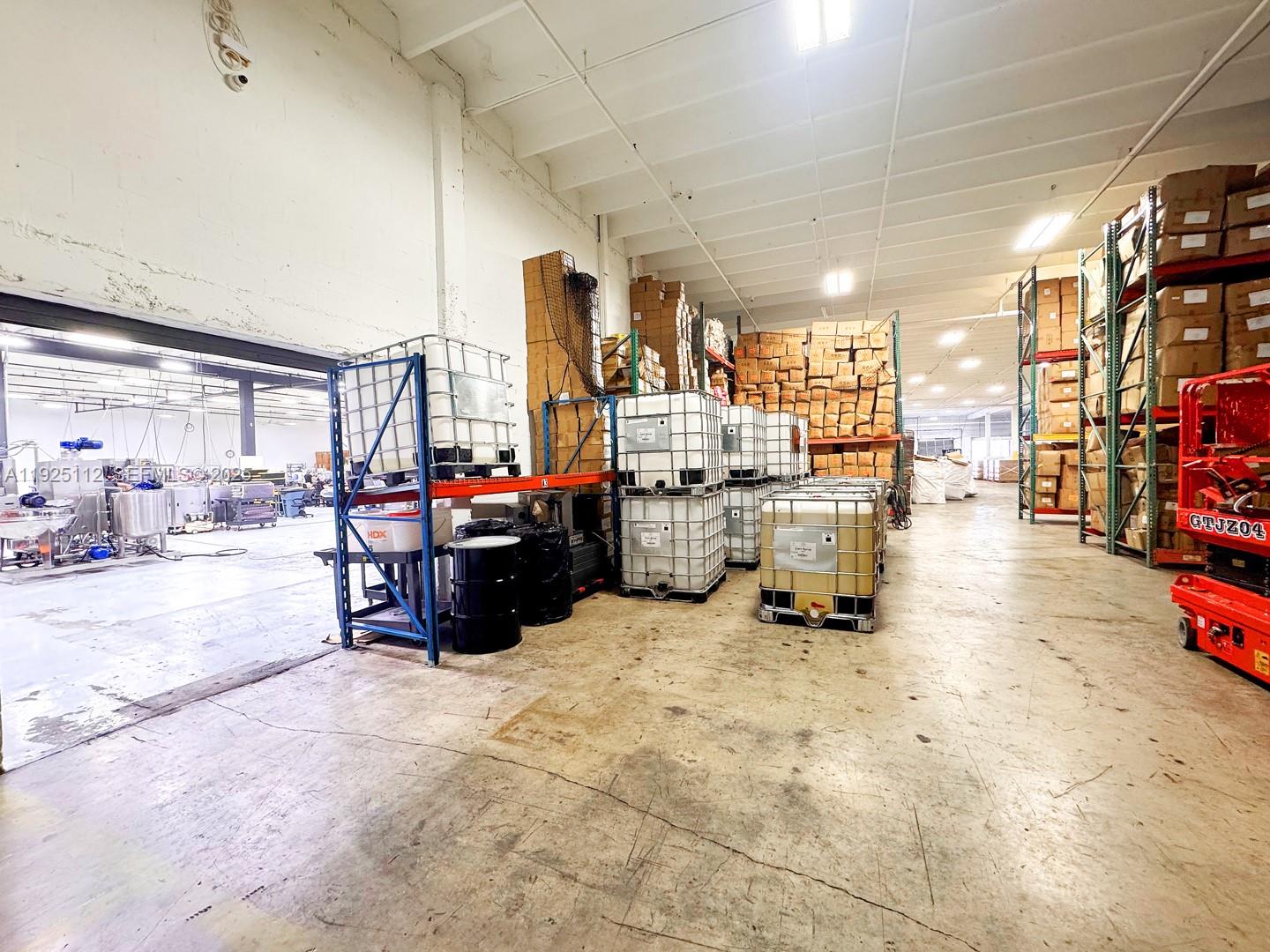 A warehouse interior features industrial shelving units, large storage containers, and a red scissor lift — 1950 NW 70th Ave # 1970, Miami FL 33126, MIAMI, FL