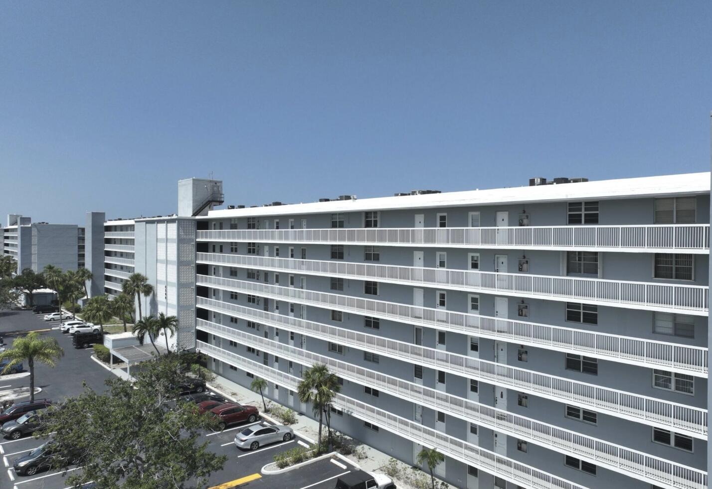 An exterior view of a multi-story apartment building with long balconies and a parking lot — 5500 NW 2nd Avenue # 718, Boca Raton FL 33487, BOCA RATON, FL