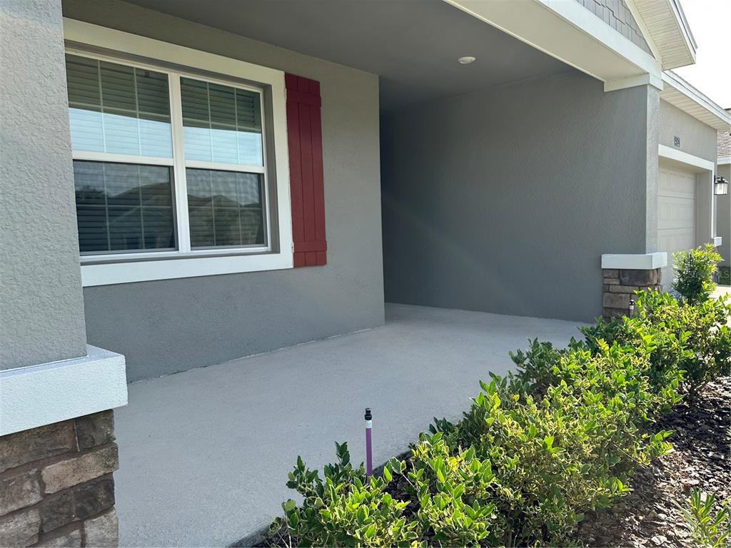 A gray house exterior features a covered front porch, a window with red shutters, and landscaping — 4162 BABBLING BROOK WAY UNIT A, KISSIMMEE, FL