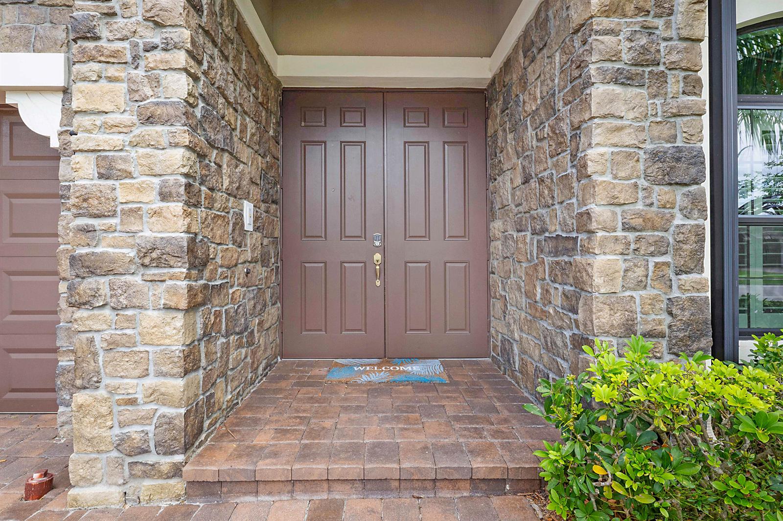 A stone-clad entryway features a brown double door and a paved porch — 8904 Sea Chase Drive, Lake Worth FL 33467, LAKE WORTH, FL