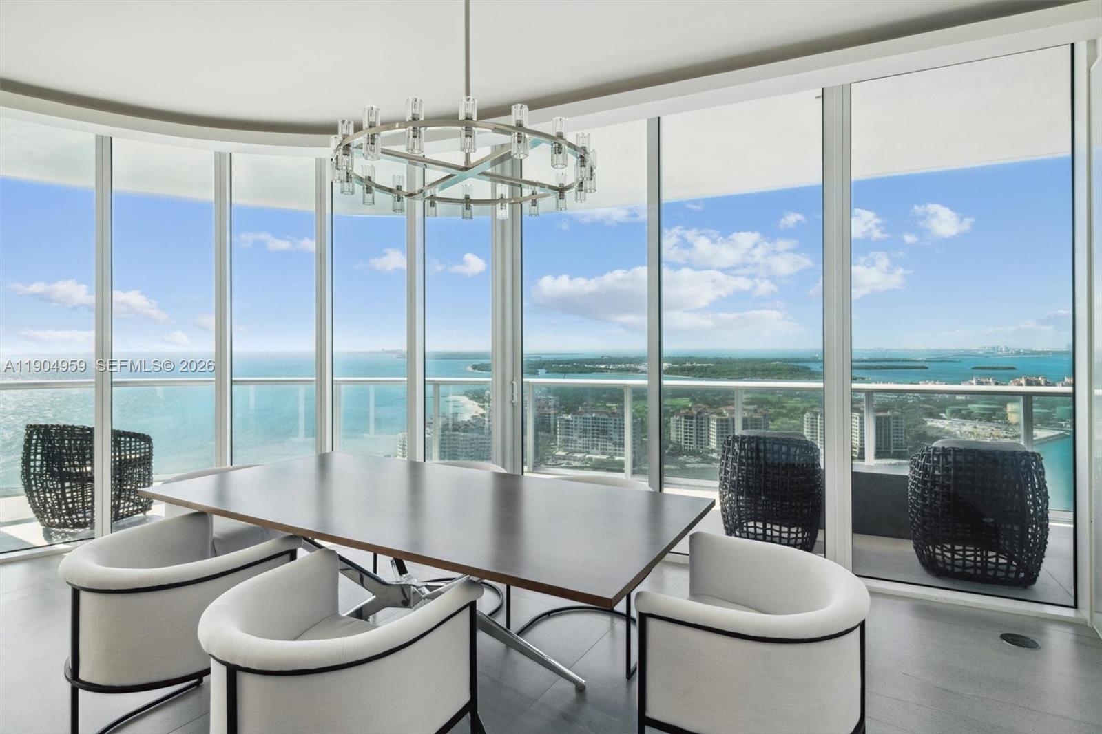 A dining room with a modern chandelier and floor-to-ceiling windows overlooking the ocean — 100 S Pointe Dr # 3203, Miami Beach FL 33139, MIAMI BEACH, FL