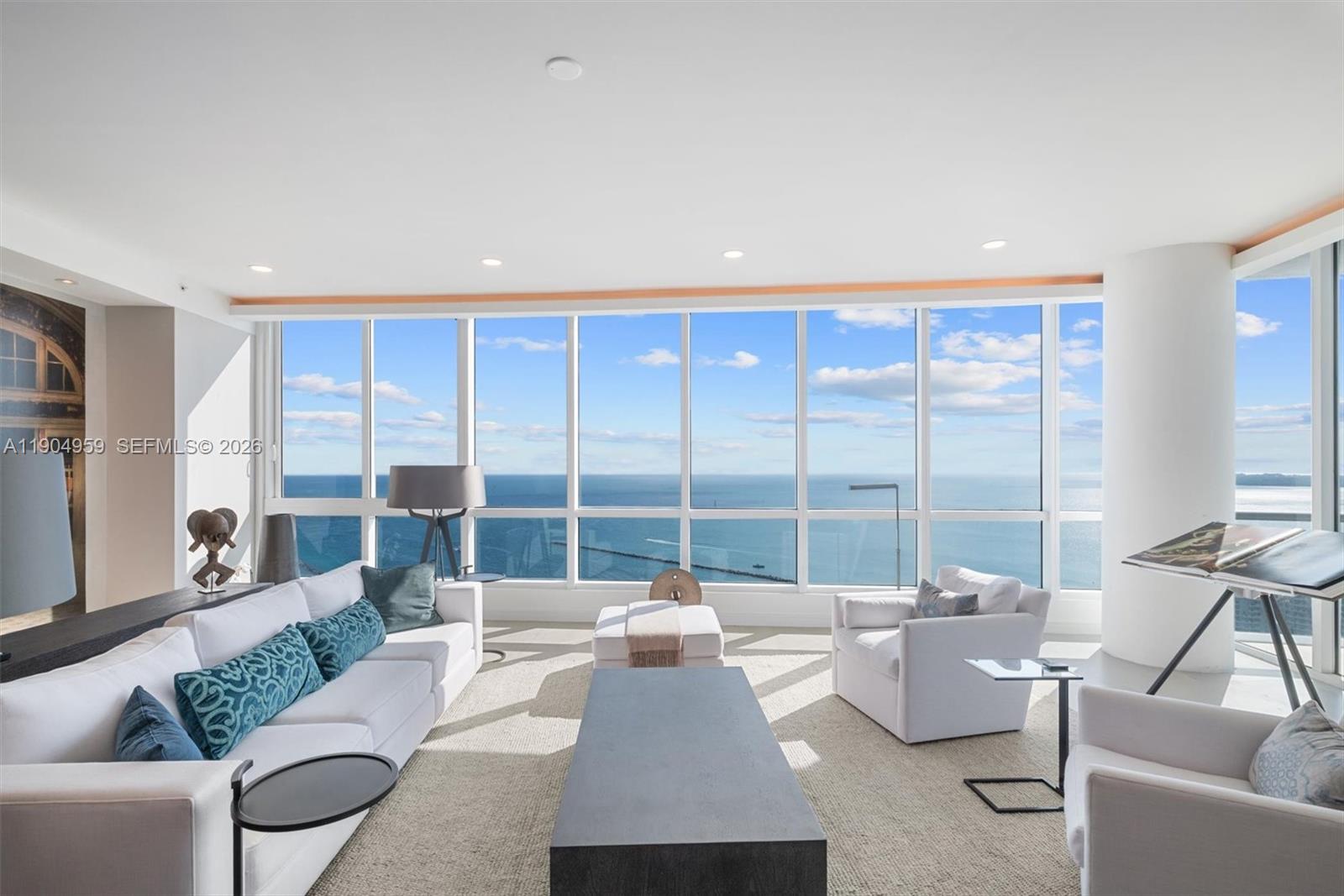 A modern living room features white furniture, a dark coffee table, and floor-to-ceiling ocean views — 100 S Pointe Dr # 3203, Miami Beach FL 33139, MIAMI BEACH, FL