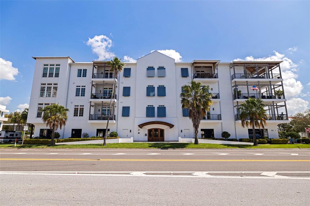 A bright living room features a large sectional sofa, wood floors, and floor-to-ceiling windows — 91 DAVIS BOULEVARD UNIT 201, TAMPA, FL