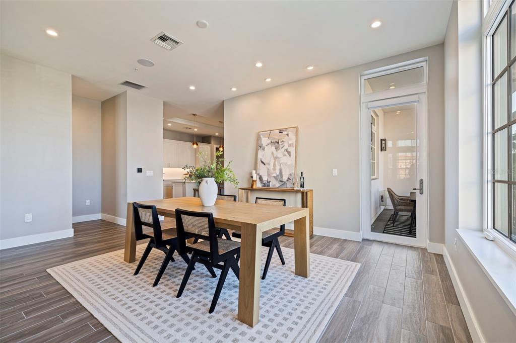 A dining room features a wooden table, black chairs, a patterned rug, and glass doors — 91 DAVIS BOULEVARD UNIT 201, TAMPA, FL