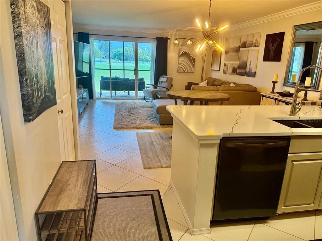 A kitchen island overlooks a living area with tile floors and a sliding glass door — 2400 FEATHER SOUND DRIVE UNIT 213, CLEARWATER, FL