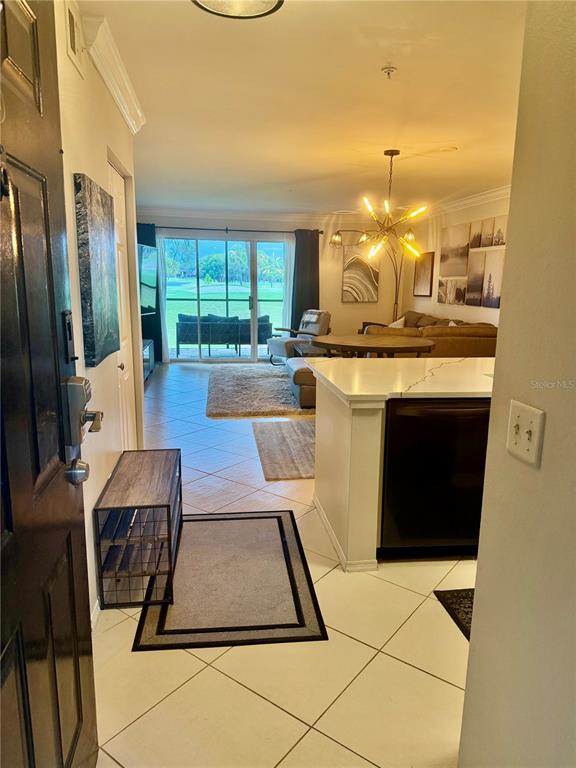 An entryway leads into a living area with tile floors, a kitchen island, and patio access — 2400 FEATHER SOUND DRIVE UNIT 213, CLEARWATER, FL