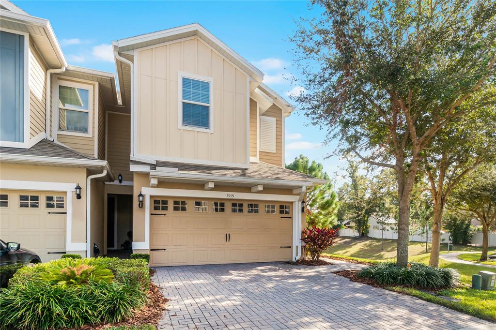 A two-story townhouse with a beige exterior, a two-car garage, and a paved driveway — 1335 E 10TH STREET, APOPKA, FL