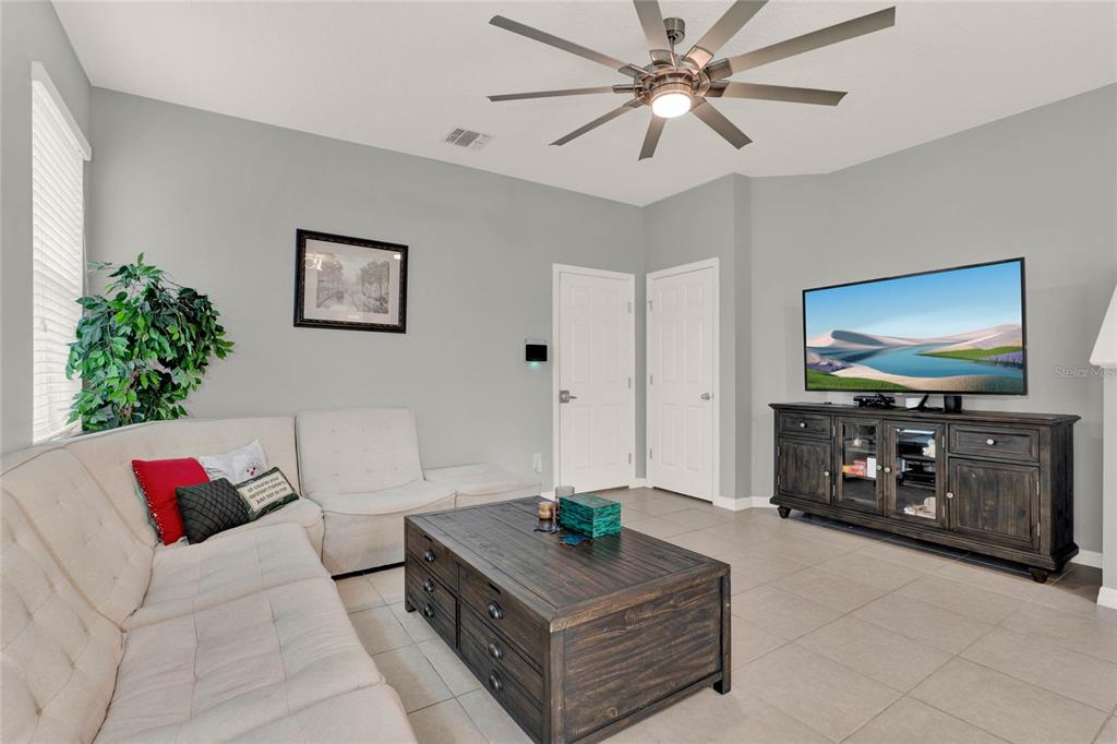 A living room features a light-colored sectional sofa, a dark wood coffee table, and a television — 1335 E 10TH STREET, APOPKA, FL
