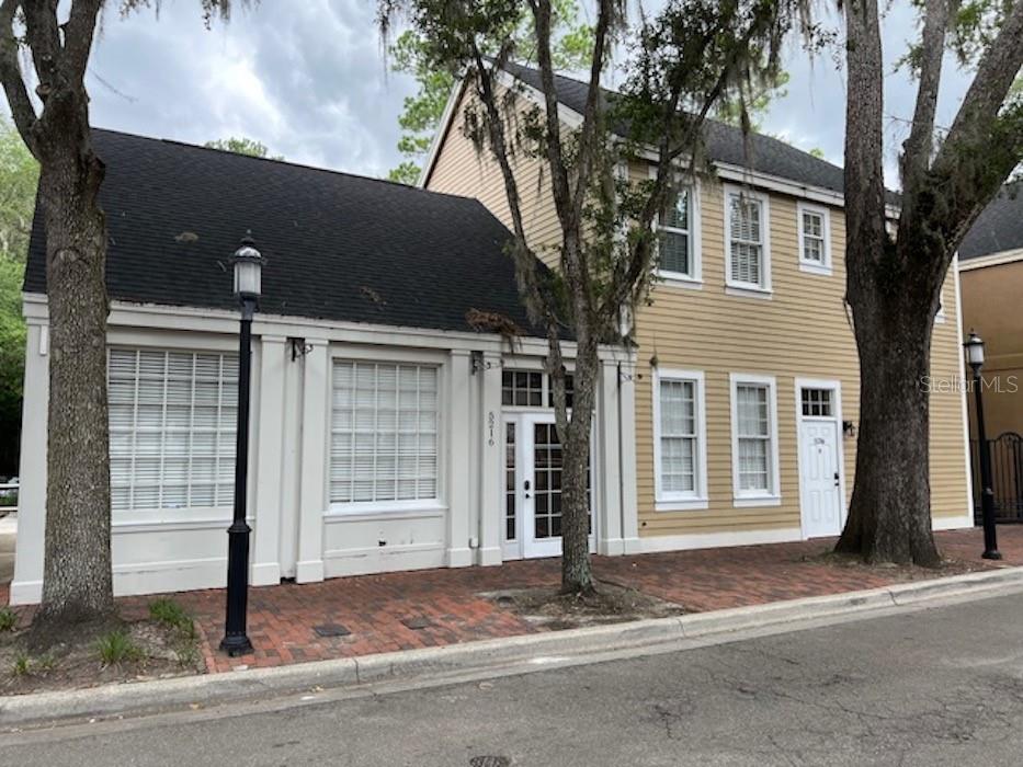 A two-story building with a brick sidewalk, tan siding, and a black shingled roof — 5216 SW 91ST TERRACE, GAINESVILLE, FL