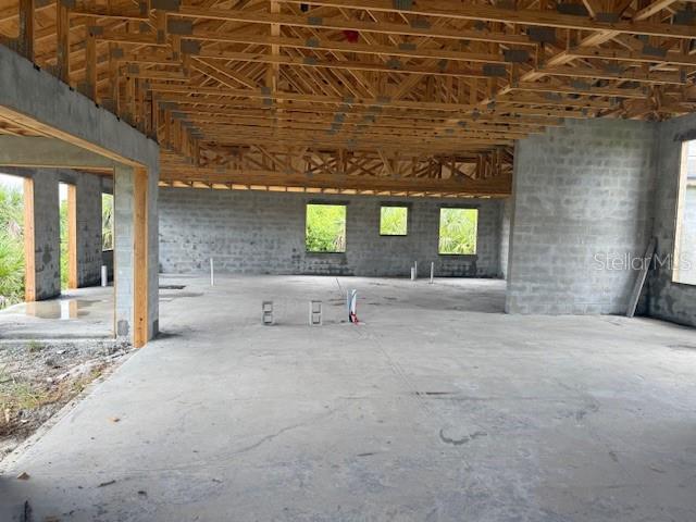 An unfinished interior space with concrete block walls, a concrete floor, and exposed wooden roof trusses — 10510 RAINSVILLE STREET, PORT CHARLOTTE, FL