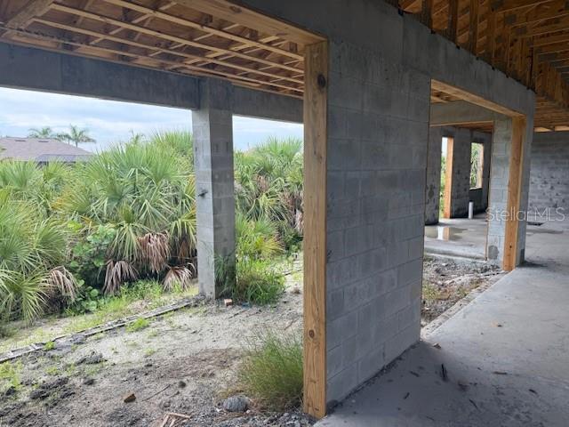 An unfinished concrete block structure with exposed wooden ceiling joists overlooks a dense palm landscape — 10510 RAINSVILLE STREET, PORT CHARLOTTE, FL