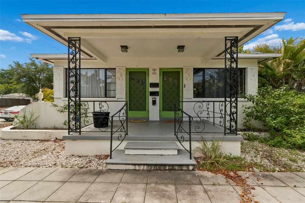 A duplex house exterior features a covered front porch with wrought iron railings and columns — 1500 30TH AVENUE N, ST PETERSBURG, FL