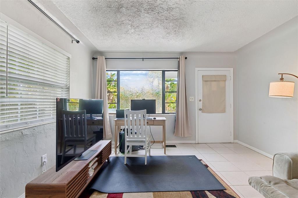 A living room features a desk by a window, a television, and tile flooring — 1500 30TH AVENUE N, ST PETERSBURG, FL