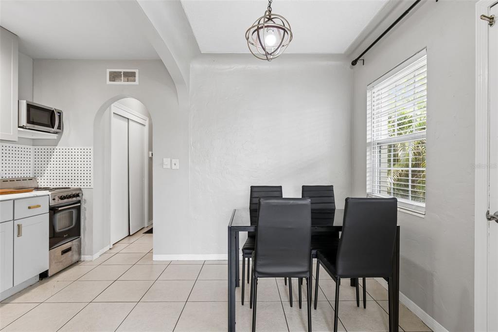 A dining area with a glass table, black chairs, tile flooring, and a pendant light — 1500 30TH AVENUE N, ST PETERSBURG, FL