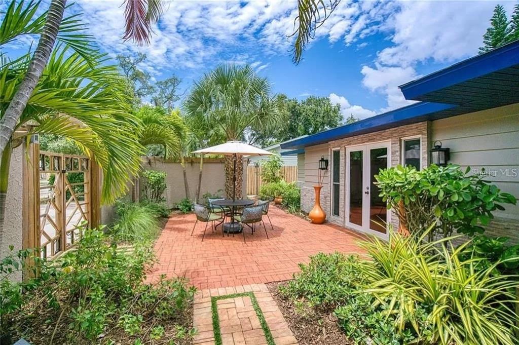 A brick patio with a dining set sits outside a house with glass doors — 1127 S OSPREY AVENUE, SARASOTA, FL