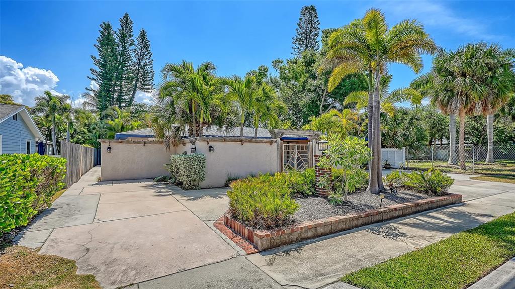 A concrete driveway leads to a stucco house exterior with palm trees and landscaping — 1127 S OSPREY AVENUE, SARASOTA, FL