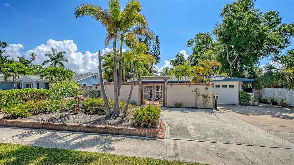 A single-story house features a stucco wall, a gated courtyard entrance, and a palm tree — 1127 S OSPREY AVENUE, SARASOTA, FL