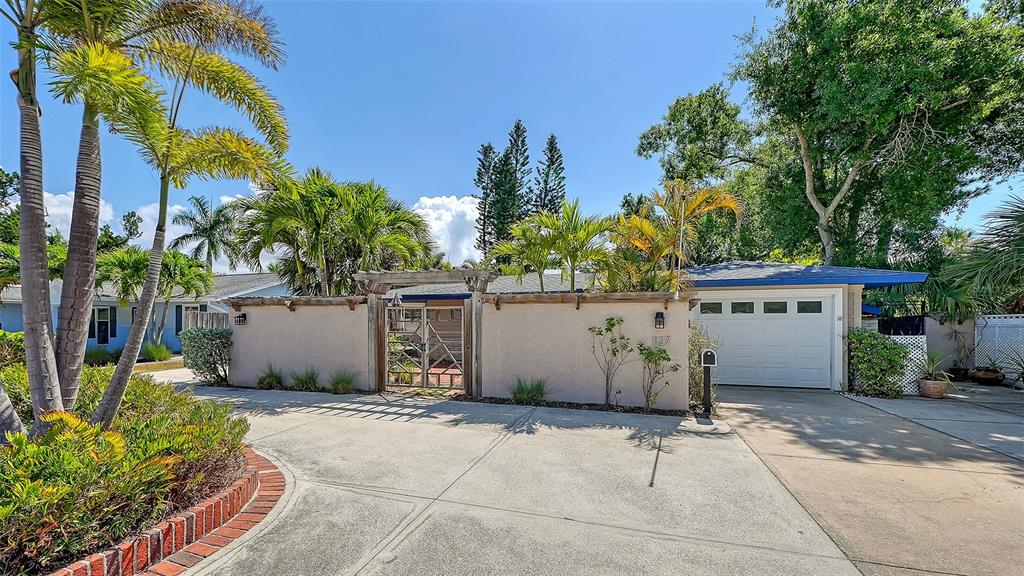 A concrete driveway leads to a house with a stucco wall, gate, and garage — 1127 S OSPREY AVENUE, SARASOTA, FL
