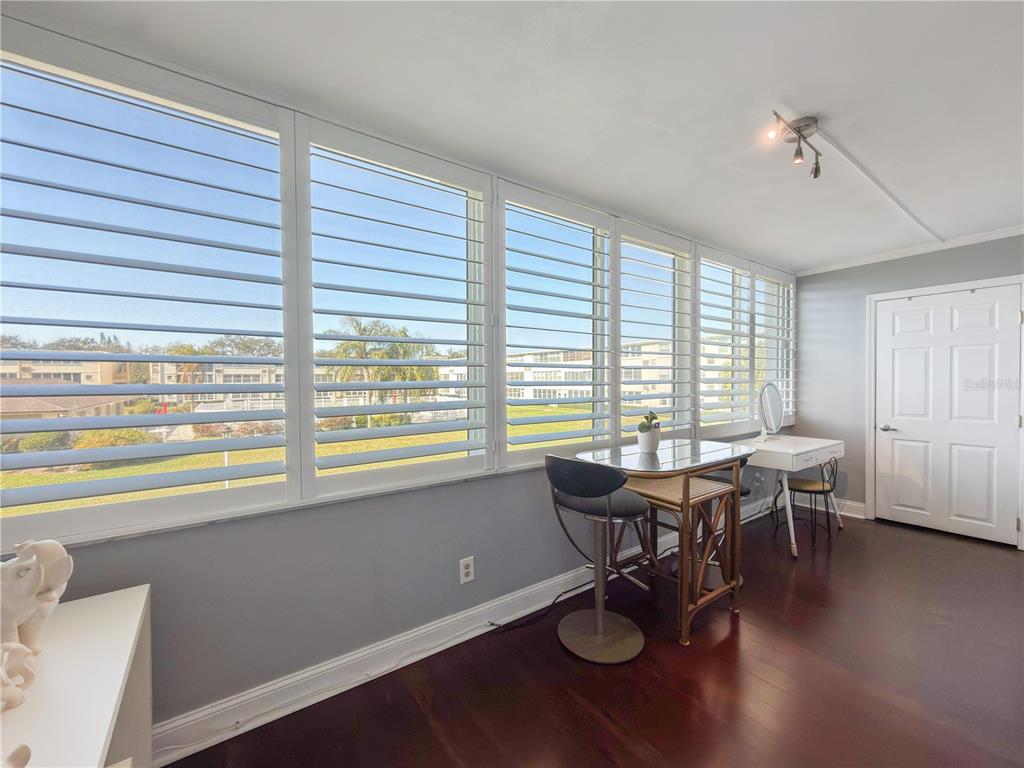 A sunroom with large shuttered windows, a small dining set, and dark wood flooring — 8100 DR MARTIN LUTHER KING JR STREET N UNIT 202, ST PETERSBURG, FL