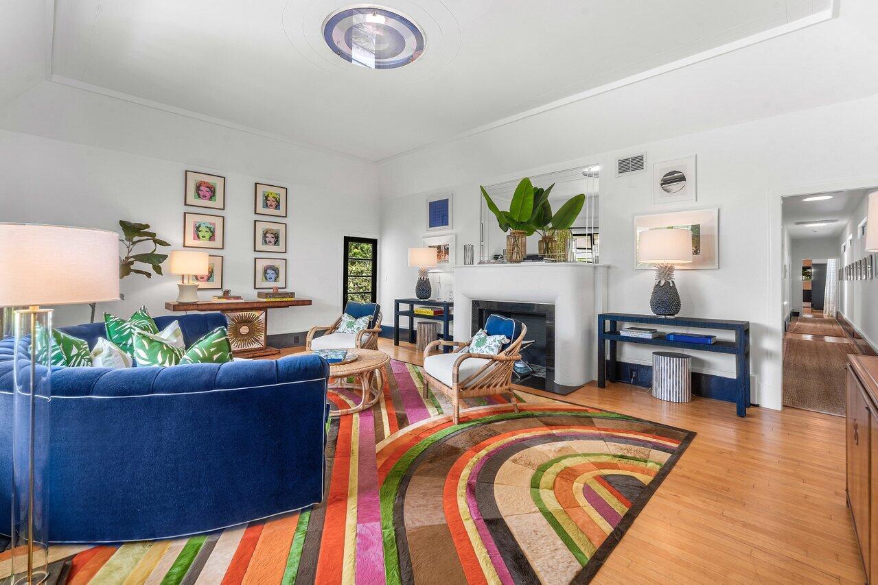 A living room features a blue curved sofa, a colorful striped rug, and a fireplace — 162 Peruvian Avenue, Palm Beach FL 33480, PALM BEACH, FL
