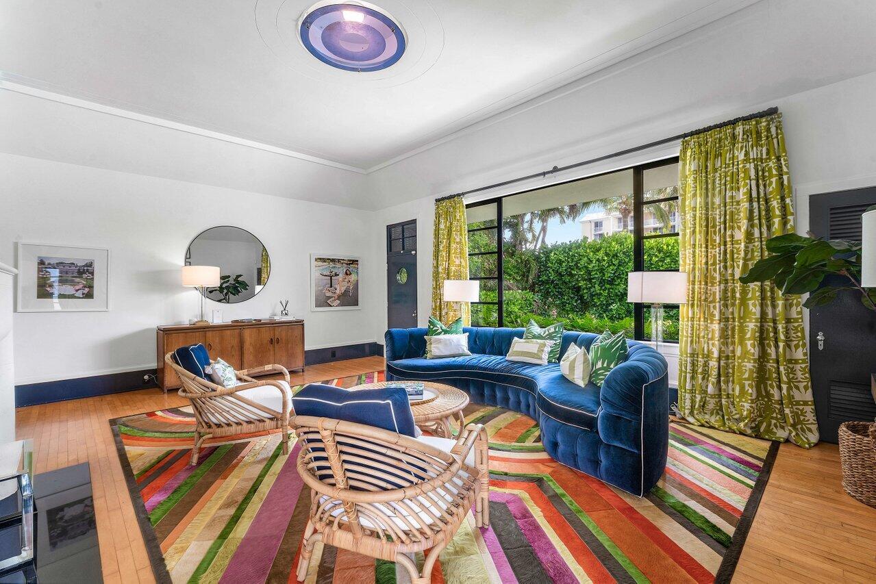 A living room features a curved blue sofa, rattan chairs, and a colorful striped rug — 162 Peruvian Avenue, Palm Beach FL 33480, PALM BEACH, FL
