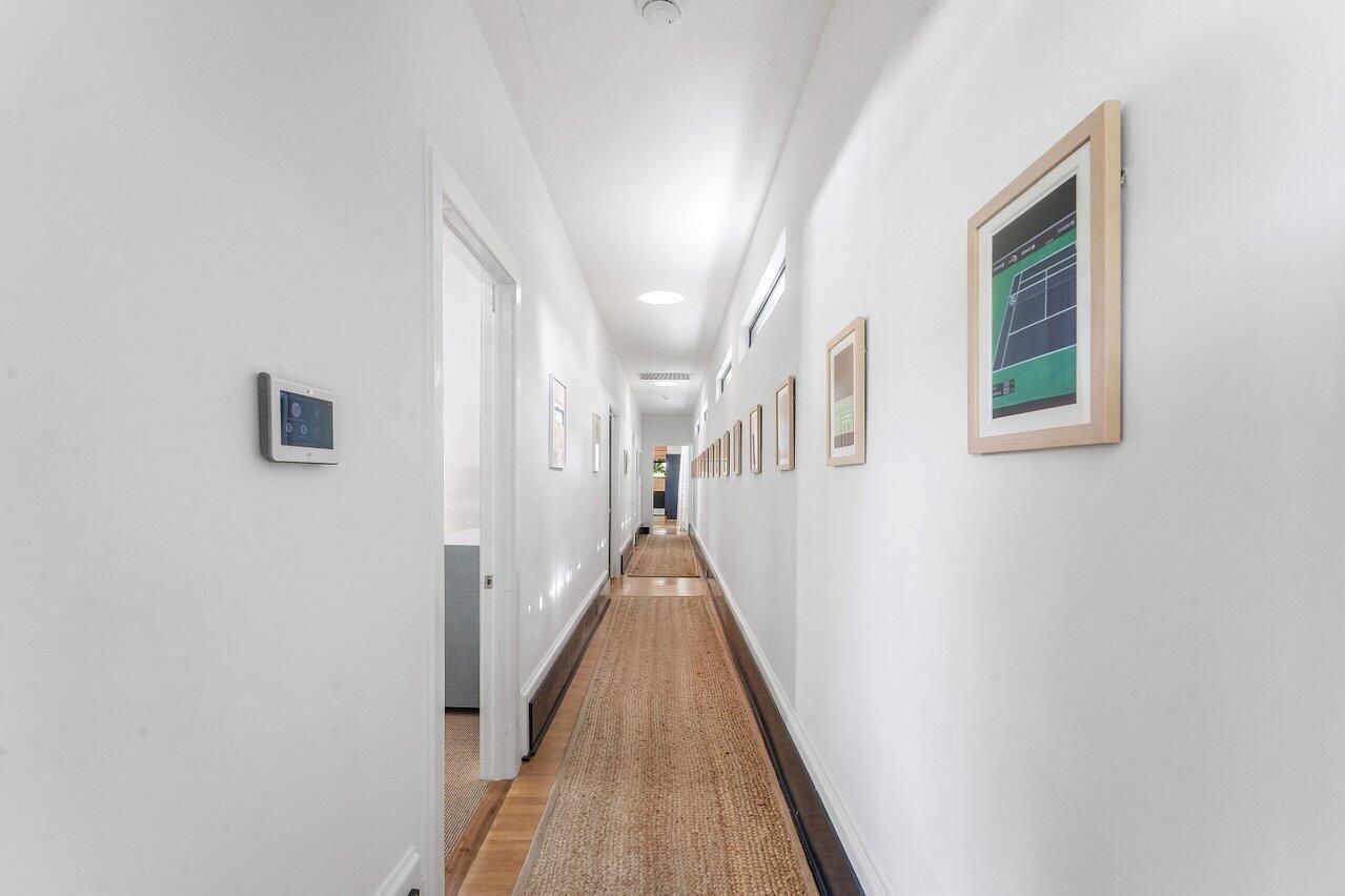 A long, narrow hallway features white walls, a jute runner, and a series of framed prints — 162 Peruvian Avenue, Palm Beach FL 33480, PALM BEACH, FL
