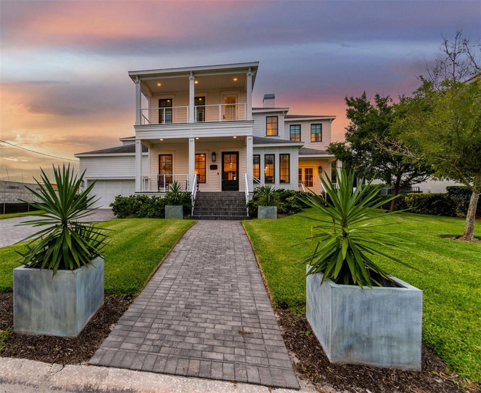 A wooden dock with a boat lift extends into a calm bay at sunset — 5811 MARINER STREET, TAMPA, FL