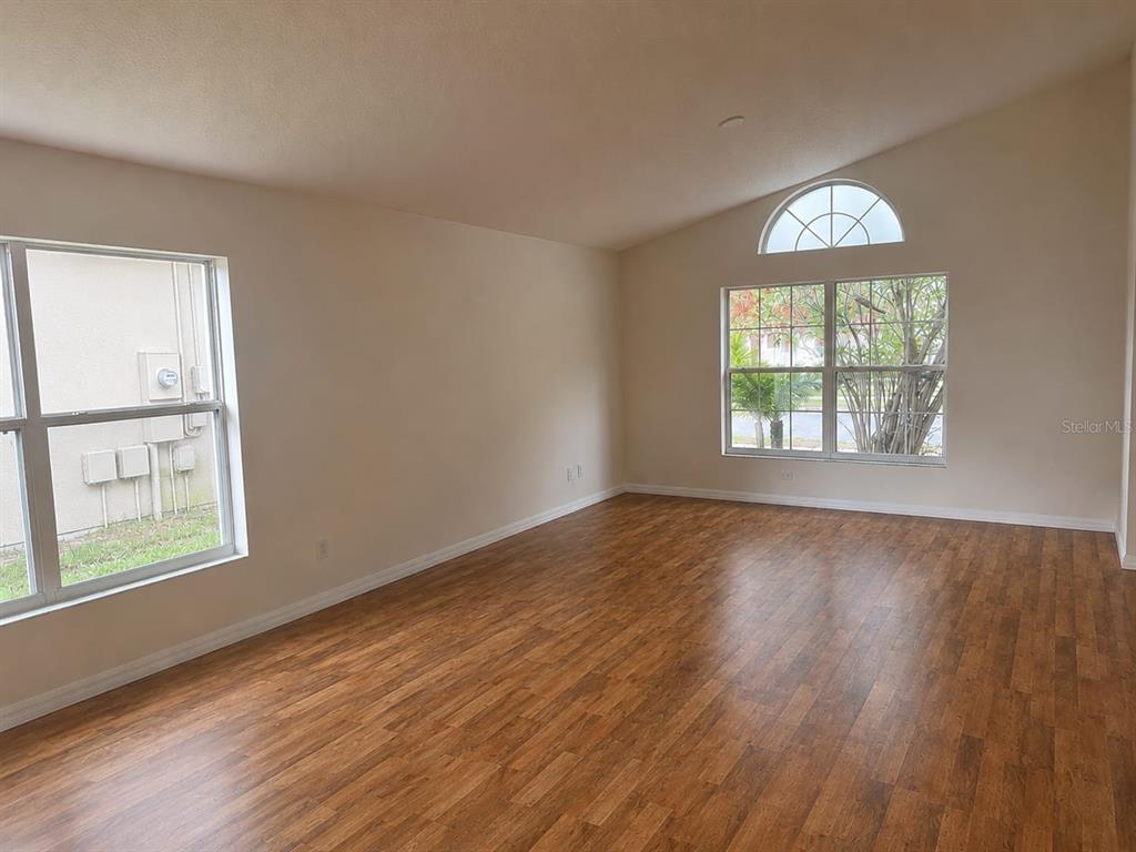 An empty room with wood-look flooring, two windows, and a vaulted ceiling — 9006 VERONA SOUND WAY, ORLANDO, FL