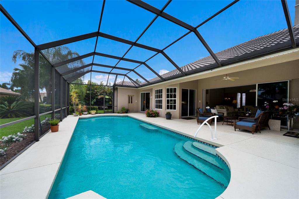 A screened-in swimming pool with steps sits on a patio next to a house — 7058 TWIN HILLS TERRACE, LAKEWOOD RANCH, FL
