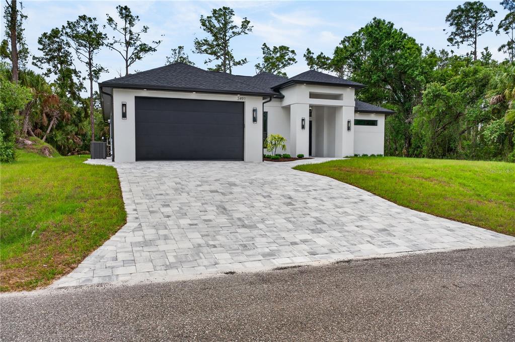 A modern single-story house with a black garage door and a paved driveway — 3491 KACHER ROAD, NORTH PORT, FL