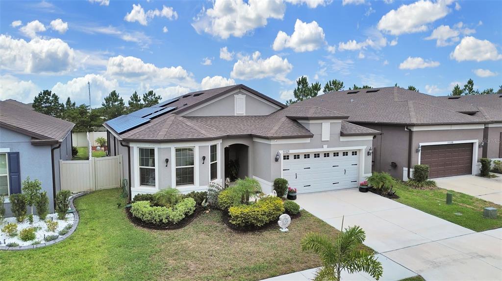 An exterior view of a single-story house with a garage, solar panels, and landscaping — 11121 GREEN HARVEST DRIVE, RIVERVIEW, FL