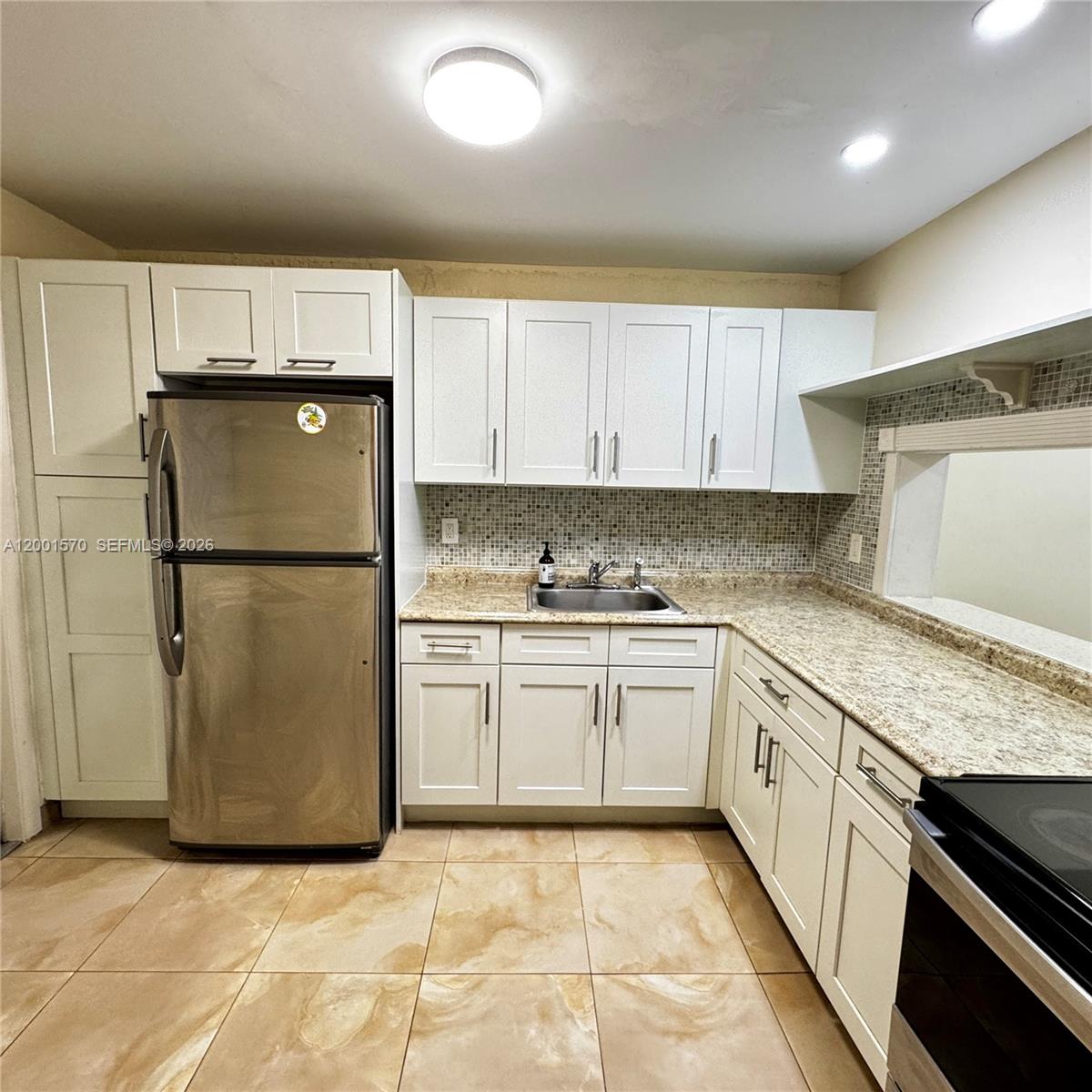 A kitchen features white cabinets, stainless steel appliances, granite countertops, and tiled flooring — 215 SE 3rd Ave # 203A, Hallandale Beach FL 33009, HALLANDALE BEACH, FL