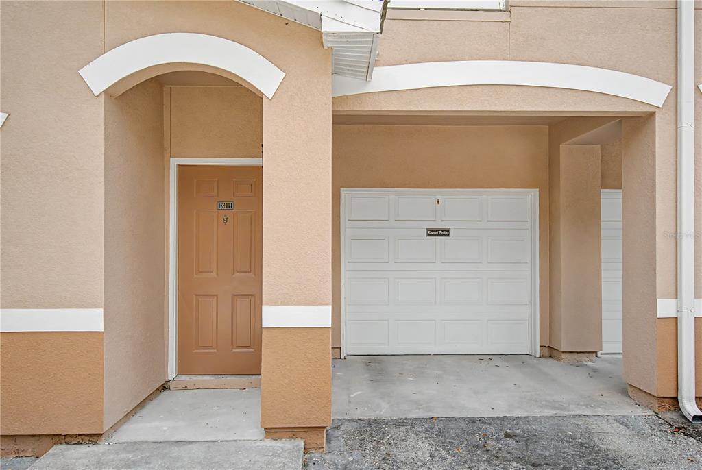 A tan townhouse exterior features a brown front door and a white garage door — 18111 VILLA CREEK DRIVE UNIT 18111, TAMPA, FL