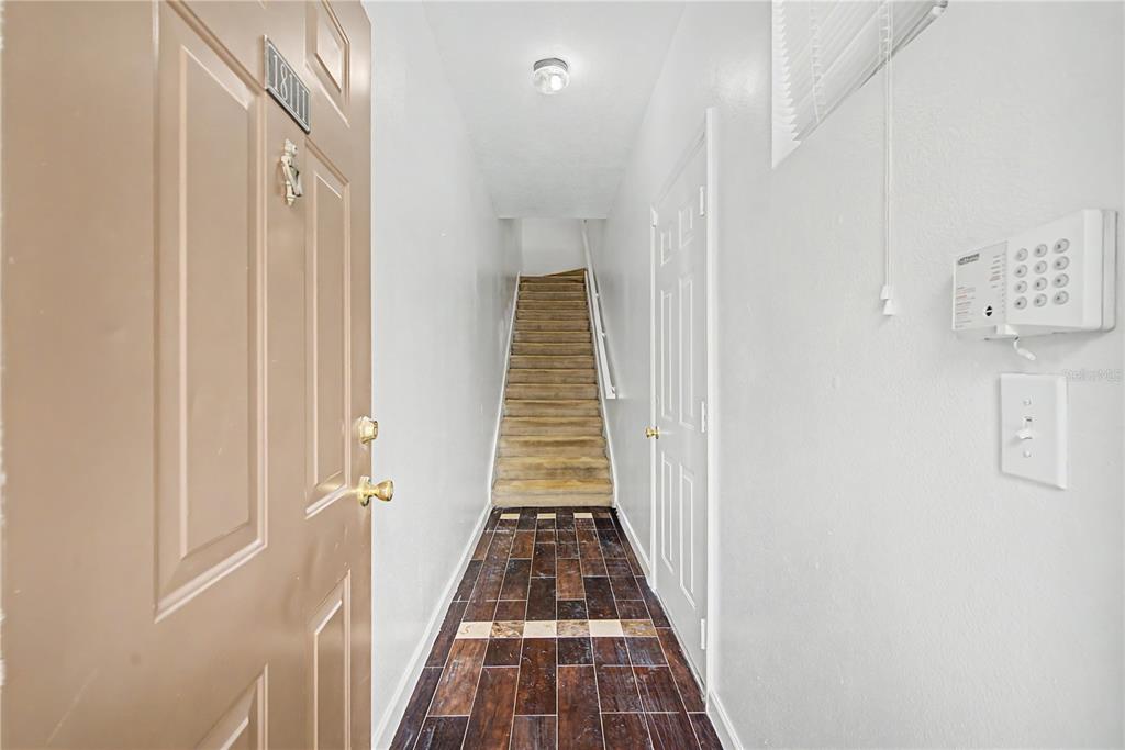 An entryway features a brown door, tiled floor, and a carpeted staircase leading upward — 18111 VILLA CREEK DRIVE UNIT 18111, TAMPA, FL