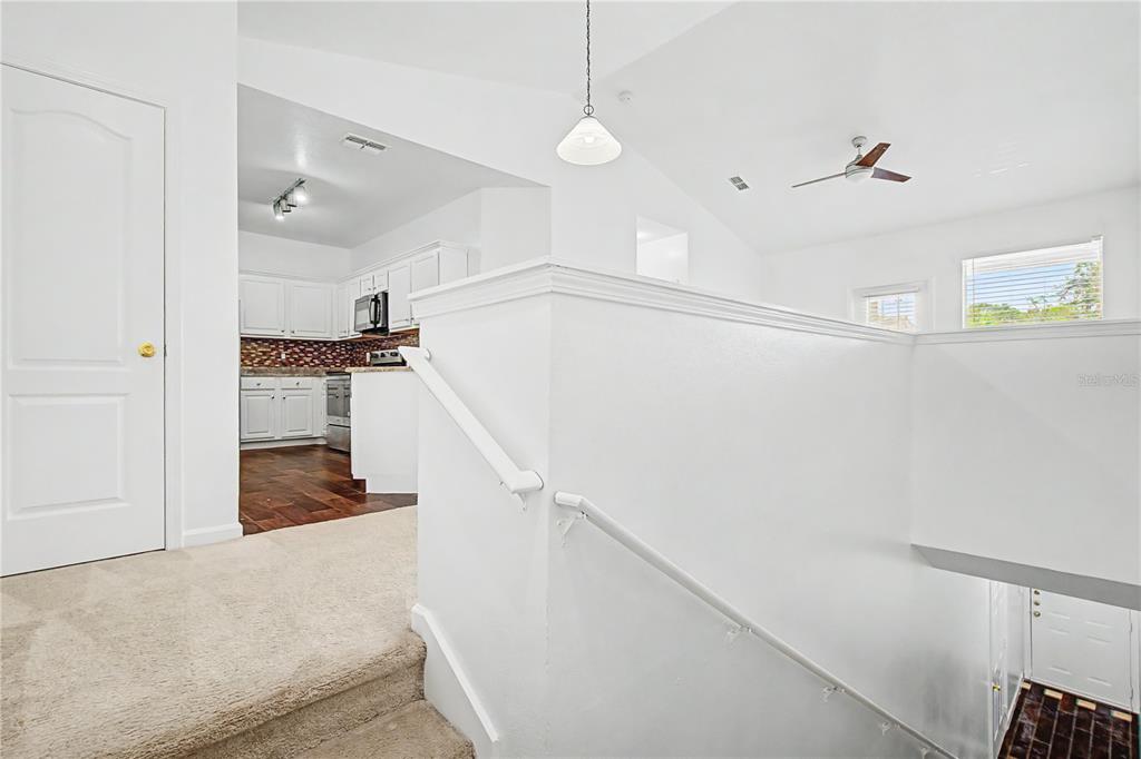 A carpeted staircase leads up to a white kitchen and an open living area — 18111 VILLA CREEK DRIVE UNIT 18111, TAMPA, FL