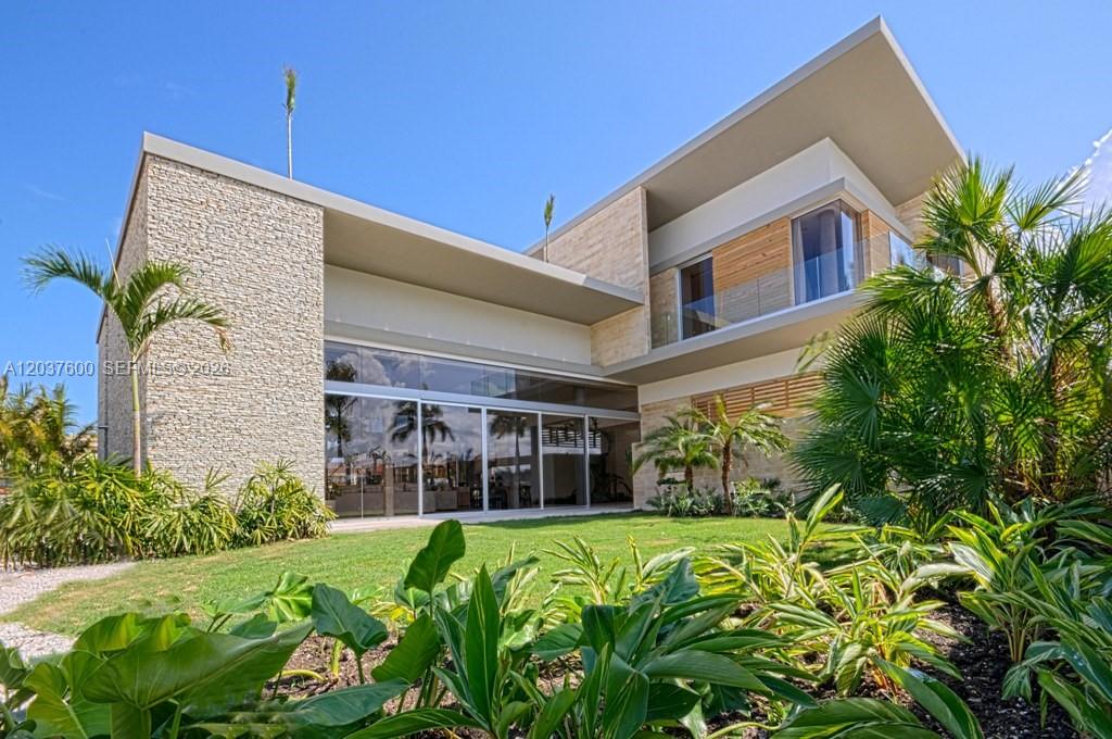A modern two-story house features stone walls, large glass sliding doors, and lush landscaping — 0 Marina cc, FL, FL