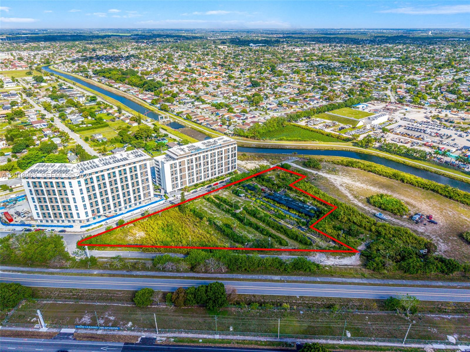 An aerial view shows a vacant, irregularly shaped lot outlined in red next to apartment buildings — 21281 SW 117th Ave, Miami FL 33177, MIAMI, FL