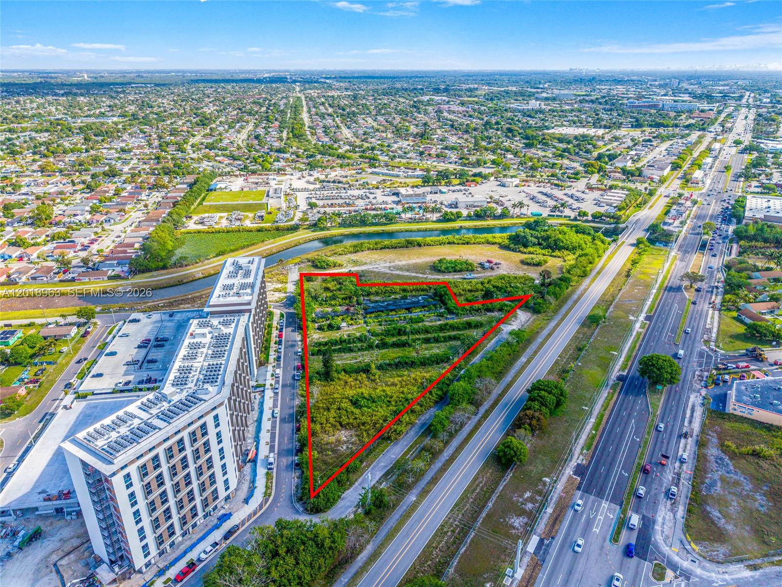An aerial view shows a triangular vacant lot outlined in red next to a large building — 21281 SW 117th Ave, Miami FL 33177, MIAMI, FL