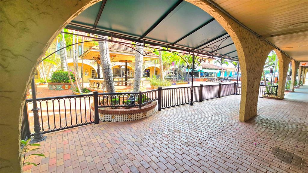A covered brick walkway features arched stucco pillars and a black metal railing — 530 US-41-BYP UNIT 20-21A, VENICE, FL