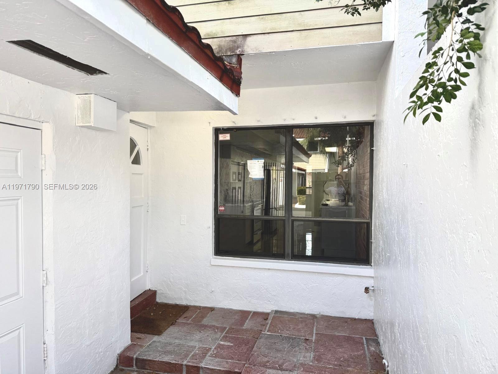 A white exterior entryway features a tiled porch, a white door, and a large window — 2700 N 34th Ave # I, Hollywood FL 33021, HOLLYWOOD, FL