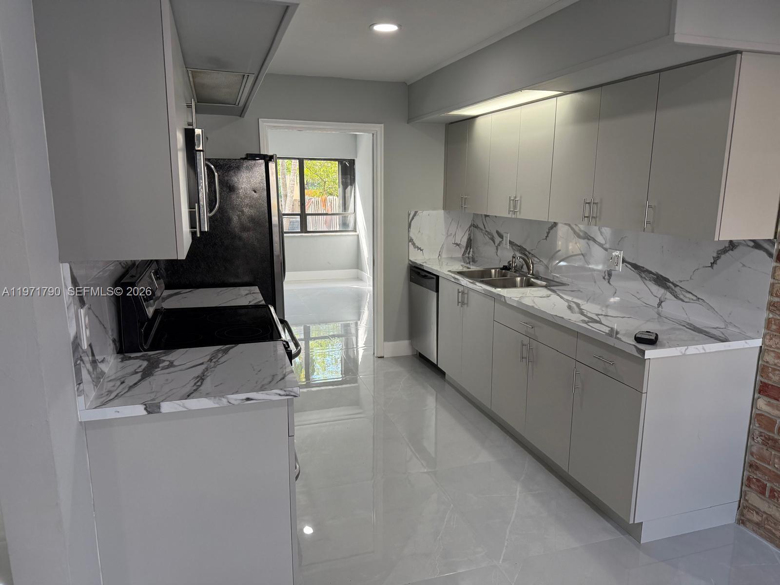 A modern kitchen features gray cabinets, marble-patterned countertops, and a matching backsplash — 2700 N 34th Ave # I, Hollywood FL 33021, HOLLYWOOD, FL